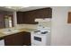 Functional kitchen featuring laminate countertops, white appliances and dark wooden cabinetry with ample storage at 5636 Dolores Dr, Holiday, FL 34690