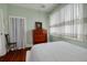 A bedroom with hardwood floors, pastel green walls, white bedding, and a window at 6207 Main St, New Port Richey, FL 34653
