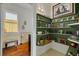 Hallway with wooden floors, shelves with knickknacks, and a small bathroom at 6207 Main St, New Port Richey, FL 34653