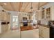 Bright kitchen featuring wood ceiling, island with butcher block counter, and cream colored cabinets at 6207 Main St, New Port Richey, FL 34653