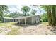 Backyard view showcases house with covered patio and mature trees, for outdoor enjoyment at 6234 Cyril Dr, Dade City, FL 33523
