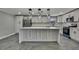 Bright kitchen featuring white cabinets, stainless steel appliances, an island, and stylish pendant lighting at 6306 Aberdeen Ave, New Port Richey, FL 34653