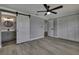 This main bedroom features an attached bathroom and a spacious closet with stylish barn door and ceiling fan at 6306 Aberdeen Ave, New Port Richey, FL 34653