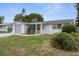 Charming single-story home with a gray driveway, front lawn, and covered entryway at 7735 Farmlawn Dr, Port Richey, FL 34668