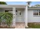 Cozy front porch featuring decorative white columns, brick flooring, and a storm door at 7735 Farmlawn Dr, Port Richey, FL 34668