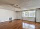 This living room has hardwood floors, a ceiling fan, and a large window at 7736 Gaston Dr, Port Richey, FL 34668