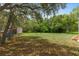 Large, partially-shaded backyard with mature trees and storage shed at 8382 Christopher Ln, Weeki Wachee, FL 34613