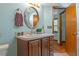 Bathroom featuring a wood vanity with a round mirror, stylish fixtures and an adjacent door at 8402 Lake Hill Ct, Spring Hill, FL 34608