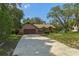 Spacious driveway leading to a well-maintained home with mature trees and a tidy front yard at 8402 Lake Hill Ct, Spring Hill, FL 34608