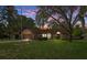 Attractive single-story home with a well-kept lawn, mature trees, and charming curb appeal at dusk at 8402 Lake Hill Ct, Spring Hill, FL 34608