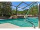 Screened-in pool with waterfall feature surrounded by lush greenery and mature trees at 8402 Lake Hill Ct, Spring Hill, FL 34608