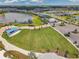 Aerial view of a large grassy recreation area with a pavilion and parking surrounded by lush landscaping at 8431 Ocean Tides Cv, Parrish, FL 34219