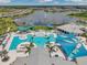 Aerial shot of community pool with lounge chairs, palm trees, and lake with fountain in the background at 8431 Ocean Tides Cv, Parrish, FL 34219