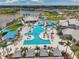 Aerial view of community pool with lounge chairs, palm trees, cabanas, and buildings with light gray roofs at 8431 Ocean Tides Cv, Parrish, FL 34219