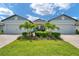 Charming single-story home featuring a well-manicured lawn, lush landscaping, and a symmetrical facade with a two-car garage at 8431 Ocean Tides Cv, Parrish, FL 34219