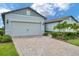 Well-maintained two car garage with brick paver driveway, tasteful lighting, and freshly trimmed landscaping at 8431 Ocean Tides Cv, Parrish, FL 34219