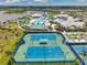 Aerial view of the community tennis courts, clubhouse, and pool, with the lake and homes in the distance at 8431 Ocean Tides Cv, Parrish, FL 34219