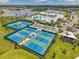 Aerial view of tennis courts and community amenities with a lake and homes in the background at 8431 Ocean Tides Cv, Parrish, FL 34219