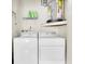 Practical laundry room featuring a washer, dryer, water heater, and convenient shelving for storage at 9334 Whitstone Ct, New Port Richey, FL 34655