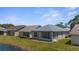 Rear view of home featuring a screened-in lanai overlooking a backyard and view of a pond at 9407 Burnam Dr, Weeki Wachee, FL 34613