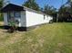 Exterior of a white home featuring green grass and a large green tree in the background at 9444 Loras St, New Port Richey, FL 34654