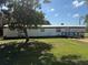 Exterior view of a single-story home featuring a well-maintained lawn, mature trees and wooden deck at 9444 Loras St, New Port Richey, FL 34654