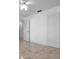 Bright bedroom featuring neutral tile floors, closet doors, and a modern ceiling fan at 9810 San Sebastian Way, Port Richey, FL 34668