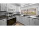 Bright kitchen featuring stainless steel appliances, gray granite countertops, and white cabinetry at 9810 San Sebastian Way, Port Richey, FL 34668