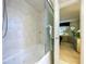 An oversized bathtub and shower in a tiled bathroom with a view into an adjoining bedroom at 10111 Glen Moor Ln, Port Richey, FL 34668