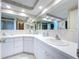 Large vanity with dual sinks, decorative wallpaper, and a view of the shower at 10111 Glen Moor Ln, Port Richey, FL 34668
