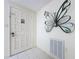 Bright foyer featuring tile flooring, white front door, and a decorative butterfly art piece on the wall at 10111 Glen Moor Ln, Port Richey, FL 34668