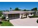 Low angle shows a single-story home's two-car garage, garden boxes and manicured shrubs at 10111 Glen Moor Ln, Port Richey, FL 34668
