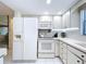 Bright kitchen featuring white appliances, cabinetry, and tile flooring at 10111 Glen Moor Ln, Port Richey, FL 34668
