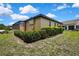 Home's back exterior featuring screen enclosed patio and manicured shrubbery in a well kept lawn at 10155 Duffy Cir, Weeki Wachee, FL 34613