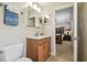 Well-lit bathroom with a wood vanity, modern fixtures, tile flooring, and a glimpse into an adjacent bedroom at 10301 Nina Ct, New Port Richey, FL 34654