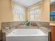 A serene bathroom features a soaking tub nestled beneath two windows with lace curtains at 10442 Ventura Dr, Spring Hill, FL 34608
