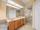 A modern bathroom features double sinks, a granite countertop, and a tiled glass-enclosed shower at 10442 Ventura Dr, Spring Hill, FL 34608
