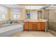 A well-lit bathroom featuring double sinks, a soaking tub, and a glass-enclosed shower at 10442 Ventura Dr, Spring Hill, FL 34608