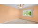 Bedroom with neutral carpet, ceiling fan, and a view of the outdoors through a window at 10442 Ventura Dr, Spring Hill, FL 34608