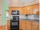 Kitchen featuring wooden cabinets and black appliances, complemented by tile backsplash at 10442 Ventura Dr, Spring Hill, FL 34608