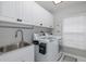 Functional laundry room with white cabinets, sink, modern appliances, and natural light at 1049 Larkin Rd, Spring Hill, FL 34608
