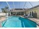 Poolside view of covered lanai with lounge chairs, outdoor kitchen, dining area, and manicured backyard at 1049 Larkin Rd, Spring Hill, FL 34608