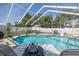 Relaxing lounge chairs surround the sparkling pool in screened enclosure with landscaped backyard at 1049 Larkin Rd, Spring Hill, FL 34608