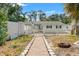 Charming backyard featuring a stone path, white picket fence, and well-maintained lawn, offering privacy at 1115 Pennsylvania Ave, Palm Harbor, FL 34683