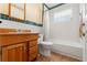 Bathroom with a wooden vanity, mirror, toilet, and shower with white tile at 1115 Pennsylvania Ave, Palm Harbor, FL 34683