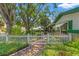 Home exterior featuring a quaint white picket fence and mature trees at 1115 Pennsylvania Ave, Palm Harbor, FL 34683