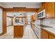 Open kitchen showcasing wood cabinets, an island, white appliances, and white tiled floors at 1115 Pennsylvania Ave, Palm Harbor, FL 34683