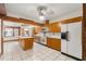 Bright kitchen featuring wood cabinets, an island, white appliances, and tiled floors at 1115 Pennsylvania Ave, Palm Harbor, FL 34683
