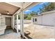 View of a screened patio area with an adjacent white building and lush green trees at 1115 Pennsylvania Ave, Palm Harbor, FL 34683