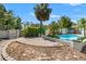 Backyard pool area with stone trim, a privacy fence, and lush tropical landscaping at 1115 Pennsylvania Ave, Palm Harbor, FL 34683